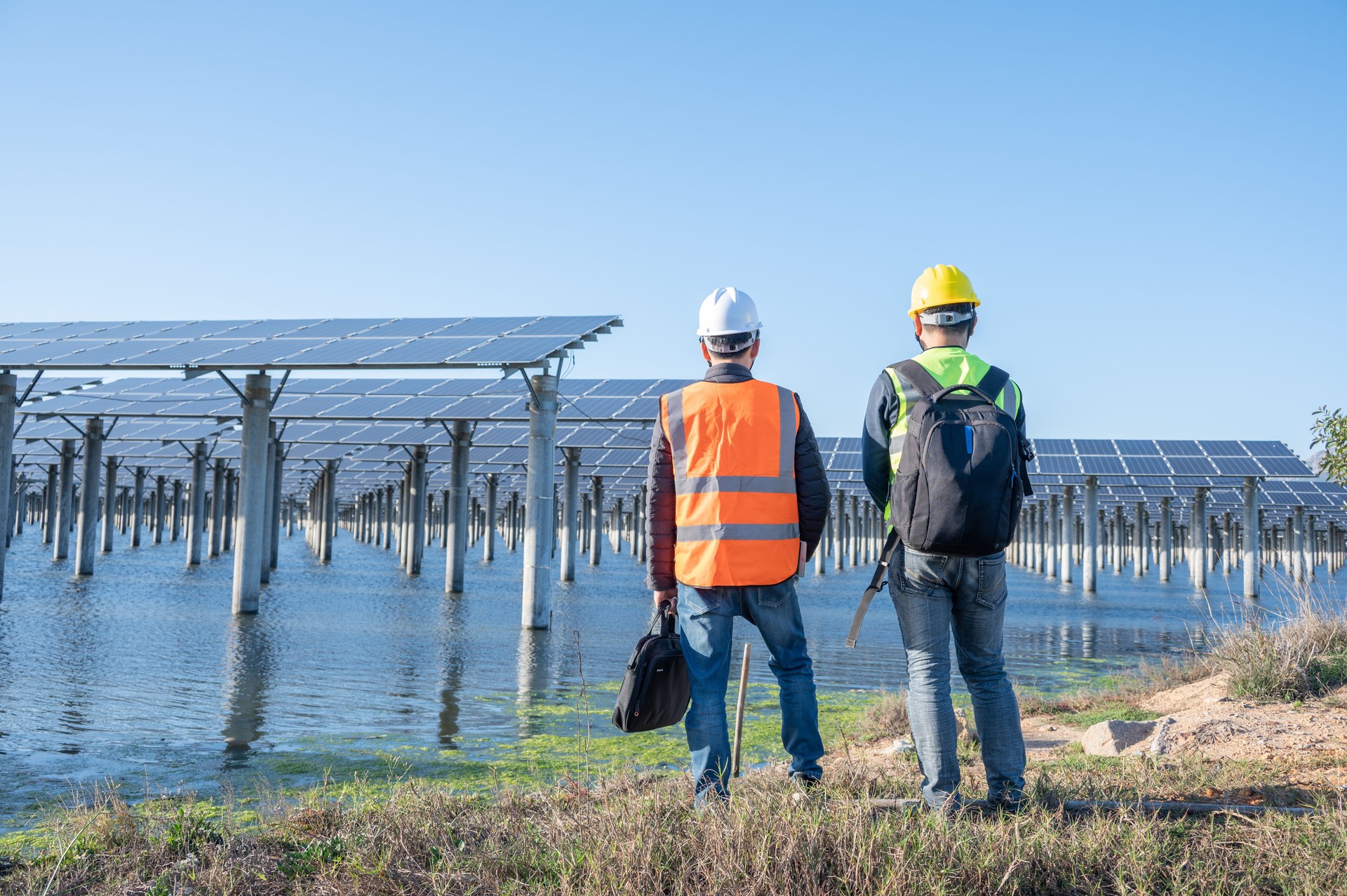 Two Asian male engineers inspected the equipment and communicated at the seaside photovoltaic solar power station
